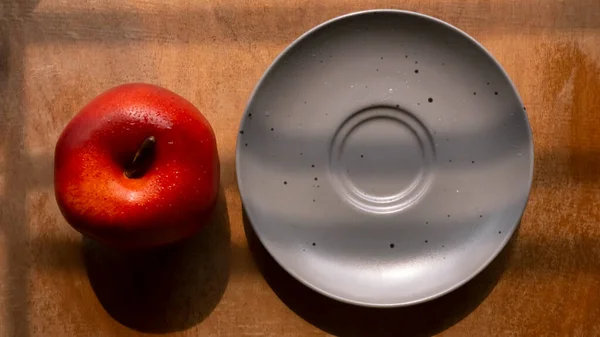 Bir elmanın üst görüntüsü ve ahşap arka planda güzel gölge efektli bir tabak. 