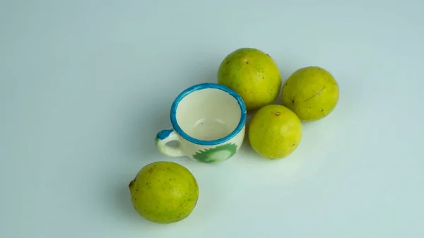 Beyaz arka planda tutulan mini bardaklı limonlar 
