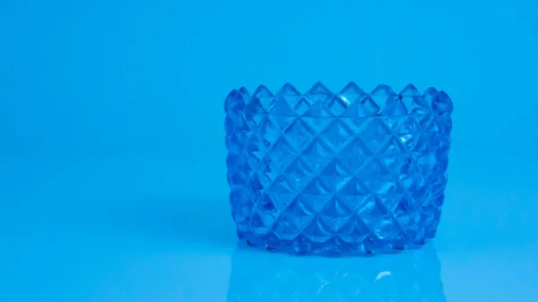 Güzel Klasik Mavi Kristal Kasesi, izole edilmiş mavi arka planda ve yerde yumuşak yansıması var.  