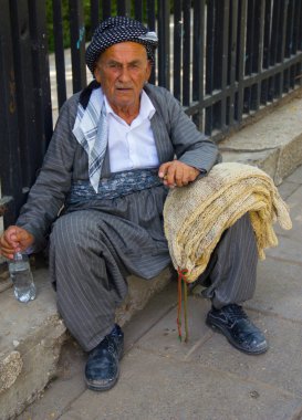 Yaz sıcağında oturarak yorgun yaşlı bir Kürt adam