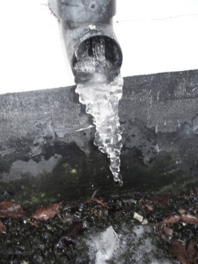 Siyah ve beyaz kışın sırasında bir pis su borusu asılı buz