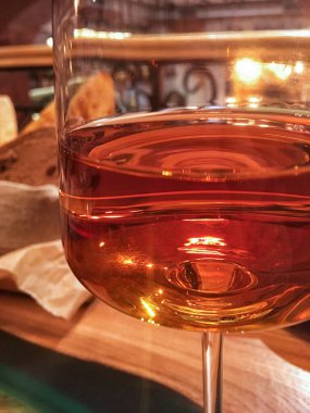 Bir restoranın masasına yakın planda gül şarabı ile cam şarap kadehi.