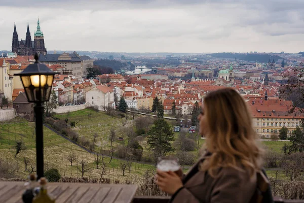 Prag, Çek Cumhuriyeti - 10 Mart 2020 Prag 'da Vysehrad manzarası, eski evlerin kırmızı kiremit çatıları, genç beyaz kız turist oturuyor ve bira içiyor