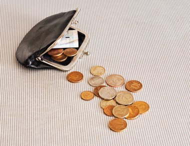 Siyah cüzdanın etrafındaki farklı ülkelerden gelen pek çok madeni para masaya saçılmıştır: dolar, pound, ruble, kuruş, sent, yuan. Tasarruf, finans kaybı, kazanç.