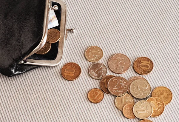 Many different coins from different countries from the black wallet are scattered around the table: dollars, pounds, rubles, pennies, cents, yuan. Saving money, losing finance, earning.