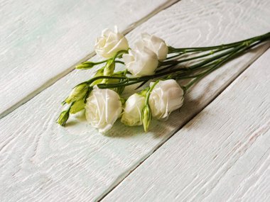 Hafif arka planda beyaz gül çiçekleri olan bir buket.