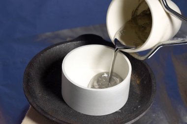 Pouring molten lead in ceramic ware. Heat-resistant ceramics. clipart