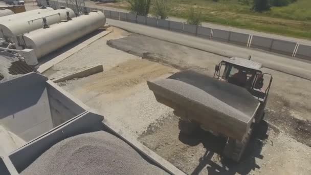 La erupción de pellets y escombros en el tanque usando un cucharón de bulldozer. Planta de asfalto — Vídeos de Stock