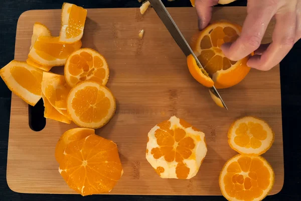 Snijden van schijfjes sinaasappelen op een snijplank. — Stockfoto