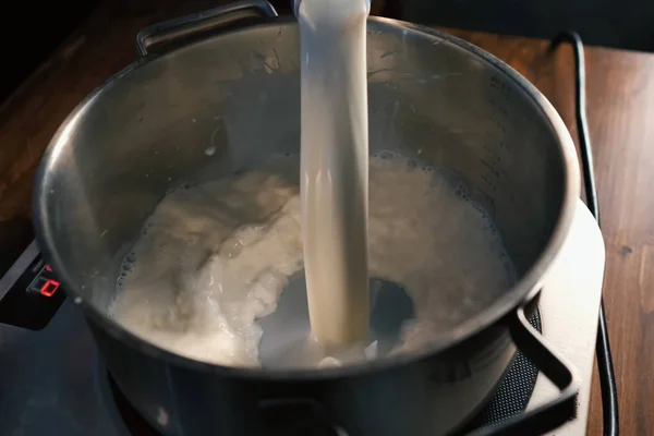 Выливание молока в кастрюлю на весах . — стоковое фото