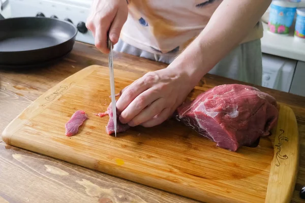 Нарезание свинины на разделочной доске ножом, куски свинины — стоковое фото