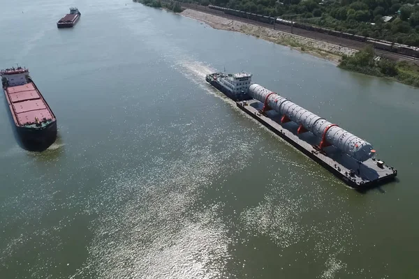 Ponadwymiarowy transport ładunków wzdłuż rzeki, Kolumna destylacyjna na barki pływaków do fabryki. — Zdjęcie stockowe