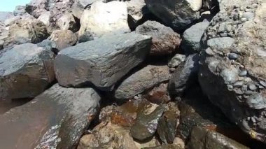 Sahilde sıralanmış büyük taşlar. Çamurlu dalgalar.