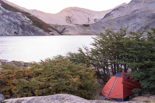 Camping orange tent in a campsite near a lagoon / Camping gear / Camping next to a lake at sunrise or sundown