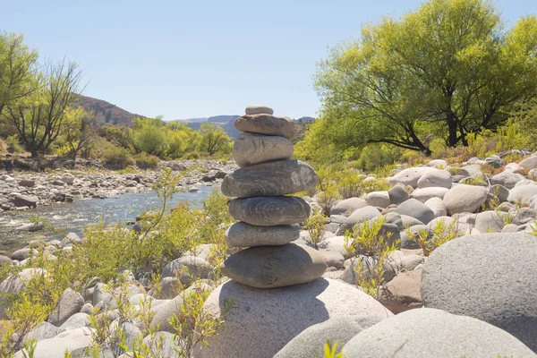 Zen stability concept, relaxation environment, outdoors tranquility, simplicity in nature. Meditation scene next to a river on a soft spring summer sunny day with a pile of stones in perfect balance