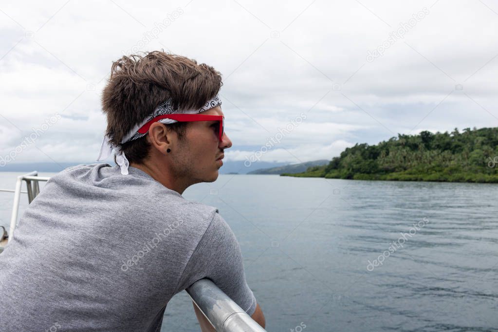 Young Man Tourist Wearing Sunglasses and Bandana Sightseeing from Boat in Fiji