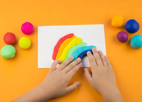 Çocuk Bir Gökkuşağı Renkli Hamuru Oluşturur Turuncu Arka Plan Malzemeler — Stok fotoğraf