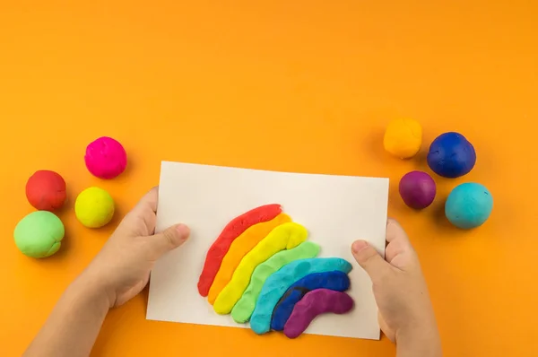 Çocuk Bir Gökkuşağı Renkli Hamuru Oluşturur Turuncu Arka Plan Malzemeler — Stok fotoğraf