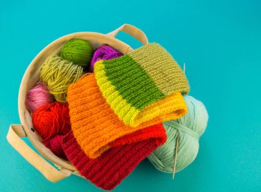 Bir gökkuşağı atkı ve şapka örgü. İğneler örgü yün topları sepetle. Mavi arka plan. En sevdiğim iş bir hobi olduğunu.