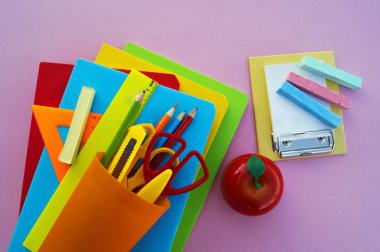 Yeniyetmenin aksesuarları pembe bir tablo üzerinde yalan. Ders kitapları ve office. Okula dönüş.