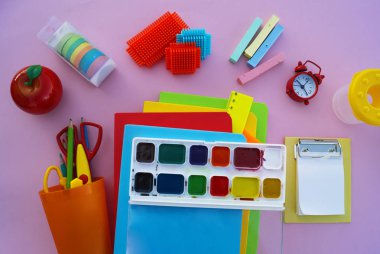 Yeniyetmenin aksesuarları pembe bir tablo üzerinde yalan. Ders kitapları ve office. Okula dönüş.