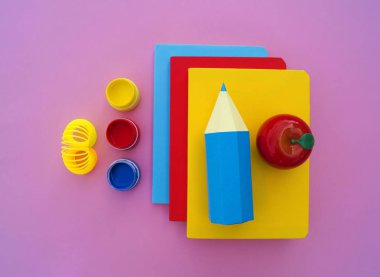 Yeniyetmenin aksesuarları pembe bir tablo üzerinde yalan. Ders kitapları ve office. Okula dönüş.