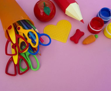 Yeniyetmenin aksesuarları pembe bir tablo üzerinde yalan. Ders kitapları ve office. Okula dönüş.