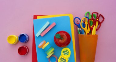 Yeniyetmenin aksesuarları pembe bir tablo üzerinde yalan. Ders kitapları ve office. Okula dönüş.