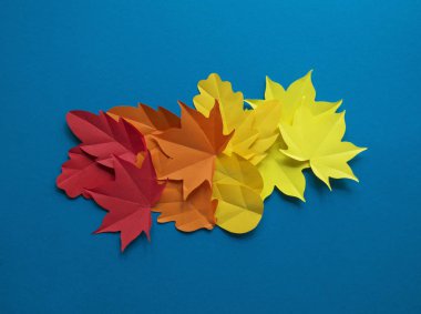 Kağıt yaprakları kırmızı, turuncu, sarı yaprak düşme düşmek. Mavi arka plan. El yapımı origami.