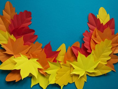 Kağıt yaprakları kırmızı, turuncu, sarı yaprak düşme düşmek. Mavi arka plan. El yapımı origami.
