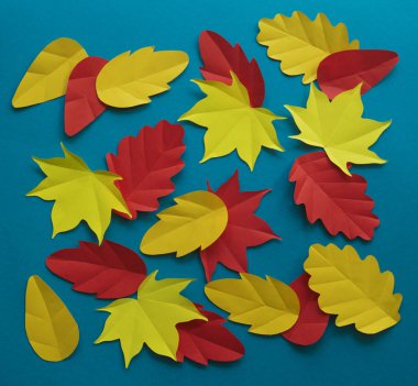 Kağıt yaprakları kırmızı, turuncu, sarı yaprak düşme düşmek. Mavi arka plan. El yapımı origami.