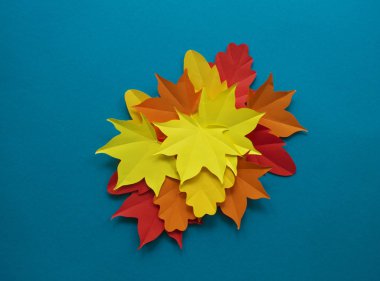 Kağıt sonbahar yaprakları bir daire içinde. Kırmızı, sarı ve turuncu yaprak. Kayıt için bir yer. Mavi arka plan.