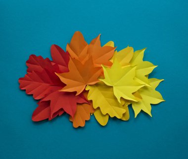 Kağıt yaprakları kırmızı, turuncu, sarı yaprak düşme düşmek. Mavi arka plan. El yapımı origami.