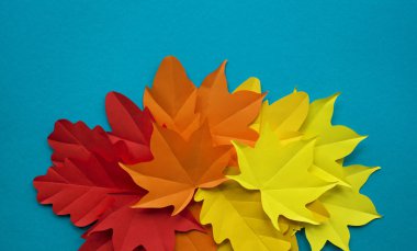 Kağıt yaprakları kırmızı, turuncu, sarı yaprak düşme düşmek. Mavi arka plan. El yapımı origami.