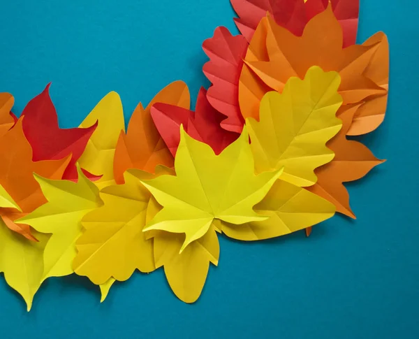 Leaves of paper fall red, orange, yellow leaf fall. Blue background. Handmade origami.