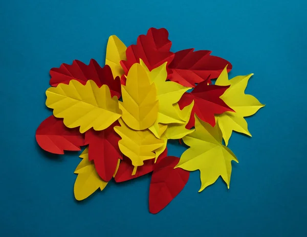 Leaves of paper fall red, orange, yellow leaf fall. Blue background. Handmade origami.