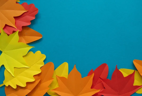 Leaves of paper fall red, orange, yellow leaf fall. Blue background. Handmade origami.
