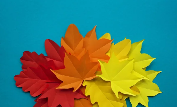 Leaves of paper fall red, orange, yellow leaf fall. Blue background. Handmade origami.