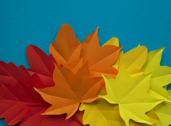 Leaves of paper fall red, orange, yellow leaf fall. Blue background. Handmade origami.