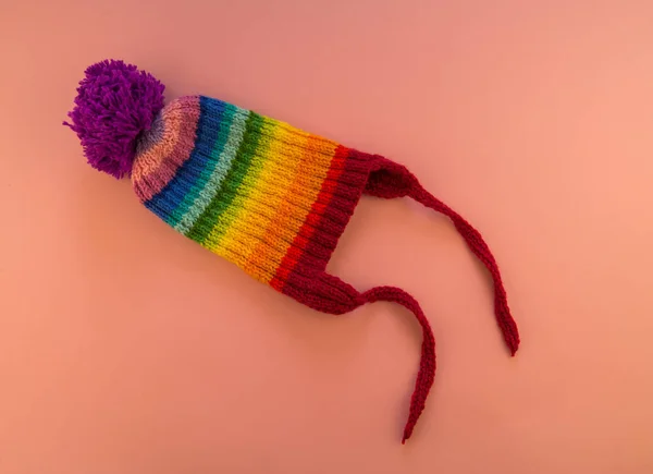 彩虹帽由羊毛制成的粉红色背景 Spase 从上面查看 带绒球的条纹针织保暖帽 — 图库照片