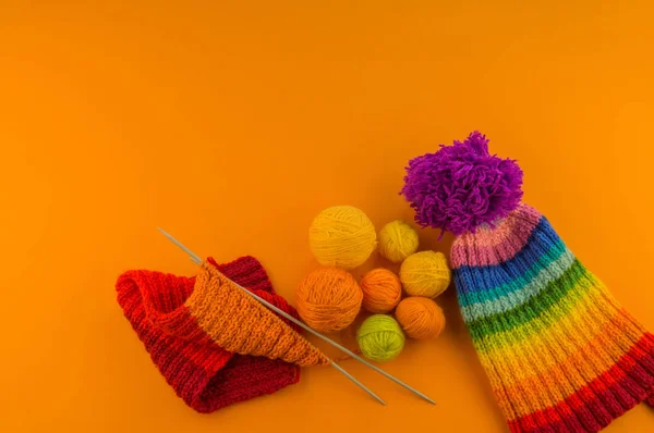 在橙色背景下由羊毛制成的彩虹帽 复制空间 从上面查看 带绒球的条纹针织保暖帽 — 图库照片