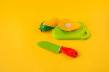 Çocuk oyuncak plastik sarı bir arka plan üzerinde. Meyve bir gemide bir bıçak ile kesmek. Anaokulu geliştirme