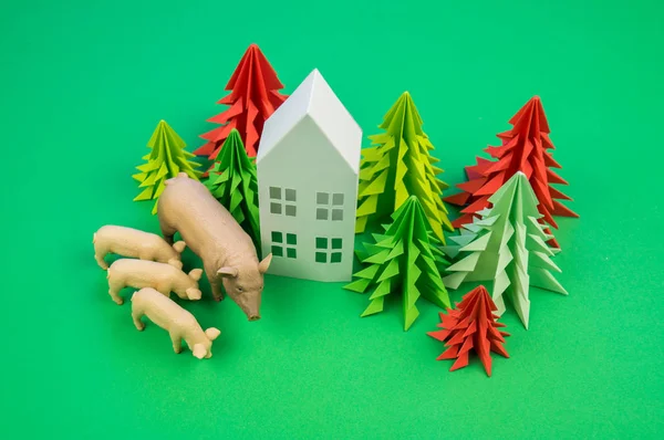 Christmas tree of paper house and pig with pigs. Decorative New Year on a green background. New Year.