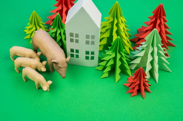 Christmas tree of paper house and pig with pigs. Decorative New Year on a green background. New Year.
