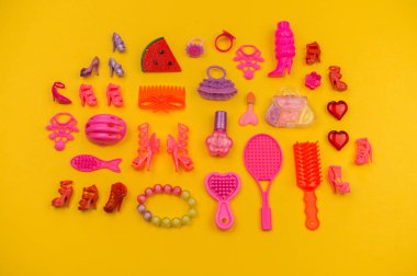 Oyuncak kız çilek şeklinde bir çanta. Çocuk Kozmetik ve takı düz pembe oyuncak sarı bir arka plan üzerinde yatıyordu. Yukarıdan görüntüleyin. Anaokulu.