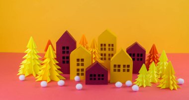 Noel orman kağıttan yapılmış. Bir ev ve bir Noel ağacı. Kartopu. Pembe ve sarı renkler.