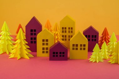 Noel orman kağıttan yapılmış. Bir ev ve bir Noel ağacı. Kartopu. Pembe ve sarı renkler.