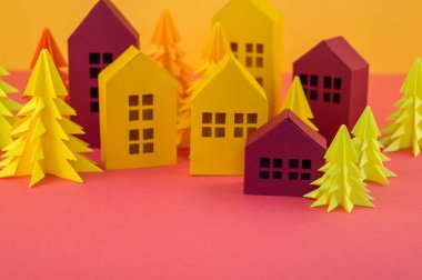Noel orman kağıttan yapılmış. Bir ev ve bir Noel ağacı. Kartopu. Pembe ve sarı renkler.