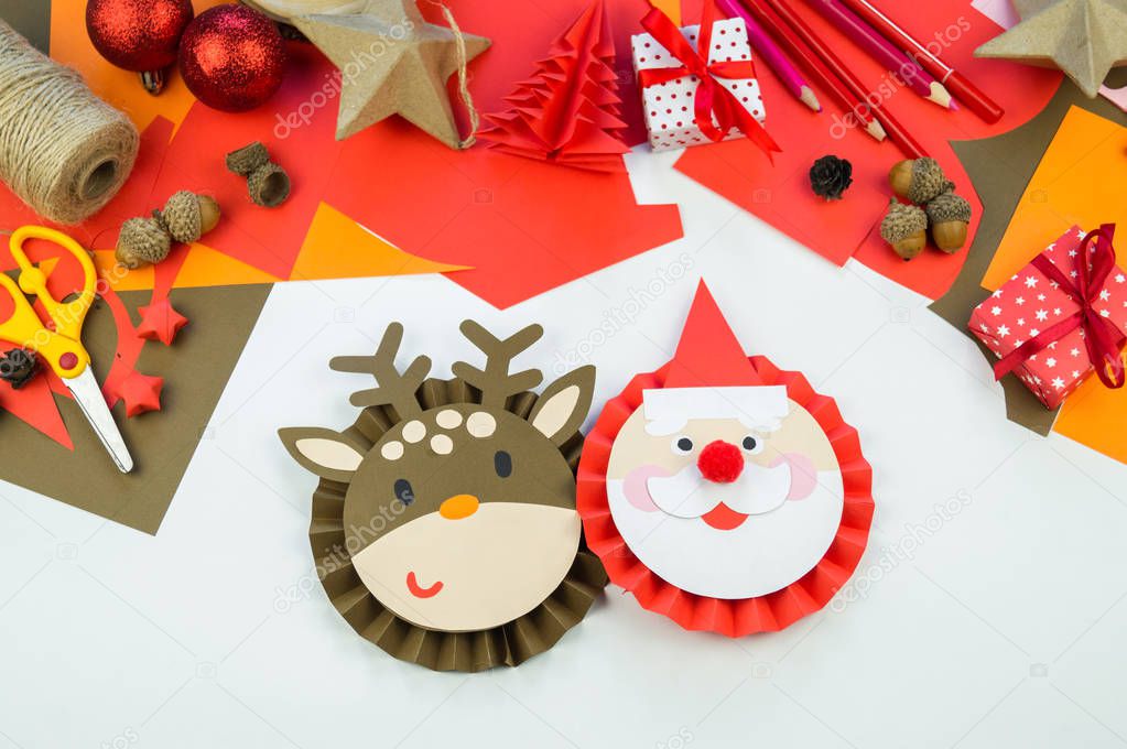 Kid makes a deer and santa claus out of paper. Christmas crafts decoration home decor. Creativity for a child.
