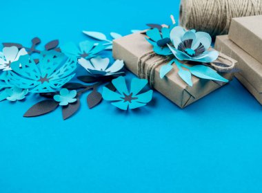Hediye kutusu craft kağıt mavi arka planda sarılmış. Sakura çiçek kağıt origami yaptı. Hediye.